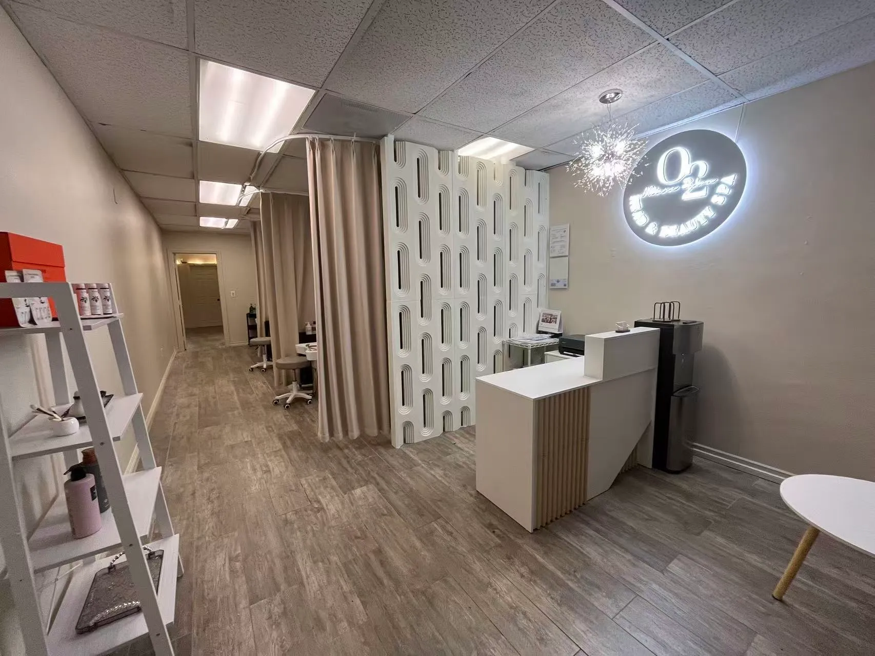 Reception at O2 Head & Beauty Spa in Arcadia: a white front desk, the lit O2 Head & Beauty Spa logo on the wall and a curtained corridor to the treatment rooms